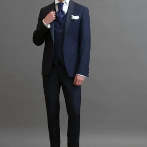 Smoking rever a scialle in sablè di lana blu abbinato
a Gilet monopetto in seta damascato blu navy